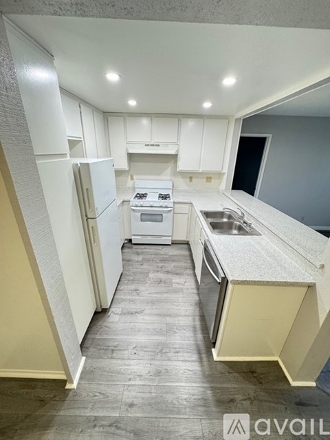 A kitchen with white cabinets and a white fridge.