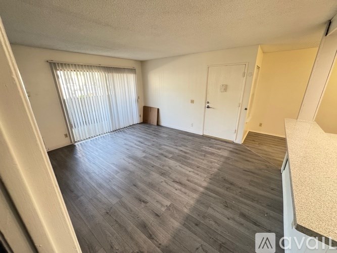 A room with wooden flooring and a window with blinds.