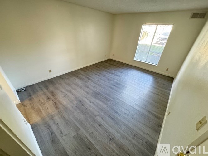 Empty room with wooden flooring and a window.
