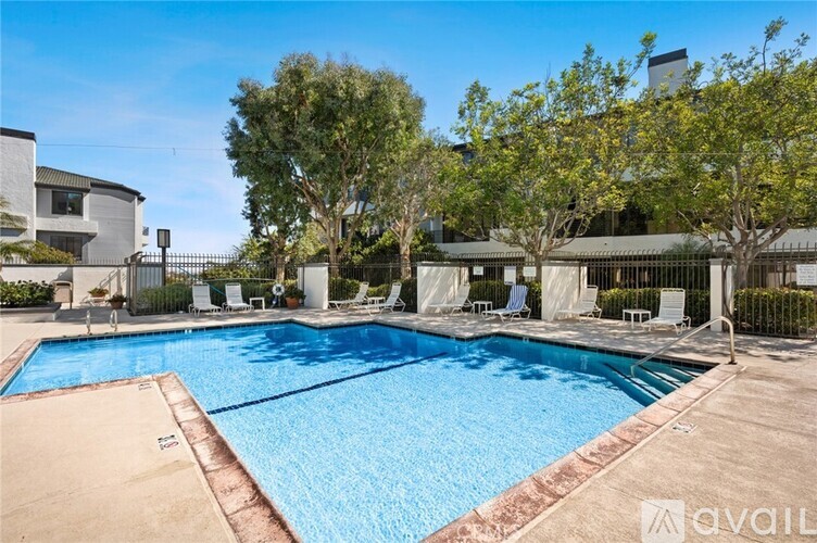 A large outdoor swimming pool surrounded by trees and lounge chairs.