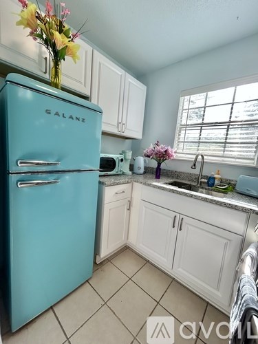 A blue Galane refrigerator in a kitchen with white cabinets.