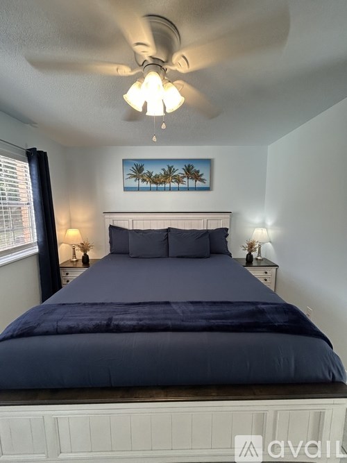 A bedroom with a bed, nightstands, and a painting on the wall.