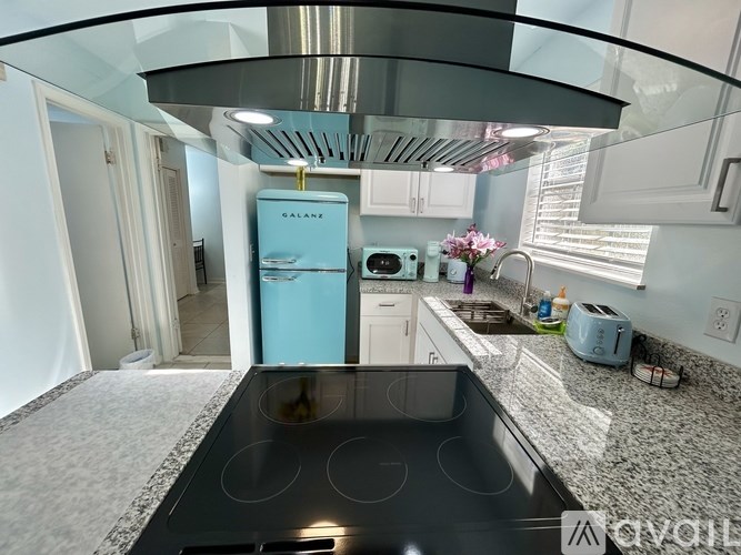 A kitchen with a blue fridge and a black stove top.