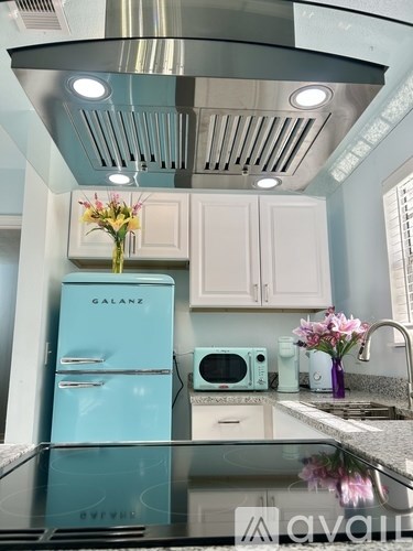 A kitchen with a blue refrigerator and white cabinets.