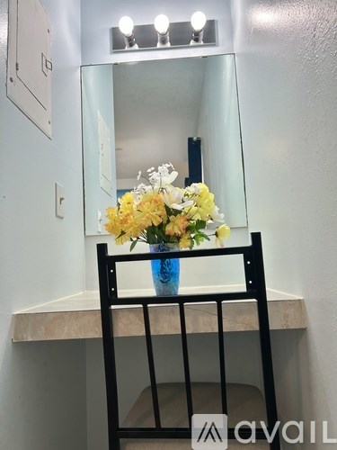 A black chair is in front of a mirror with lights on the wall.