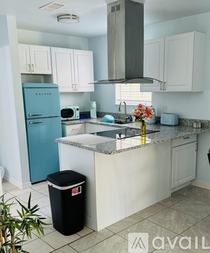 A kitchen with a blue fridge and white cabinets.