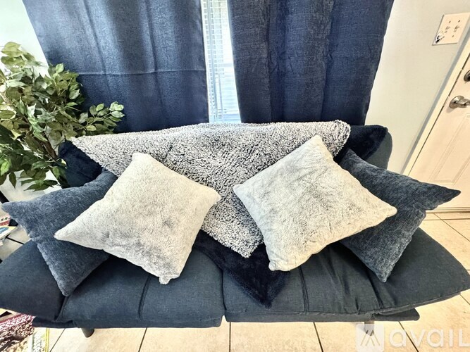 A chair with grey and black cushions and pillows.