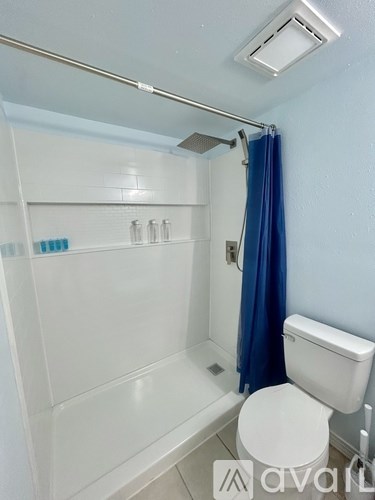 A white toilet sits next to a blue shower curtain in a small bathroom.