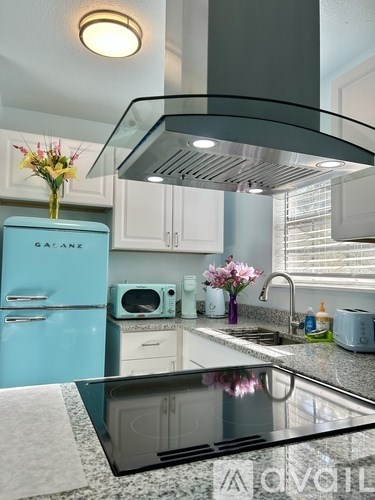 A kitchen with a blue fridge and a black stove top.