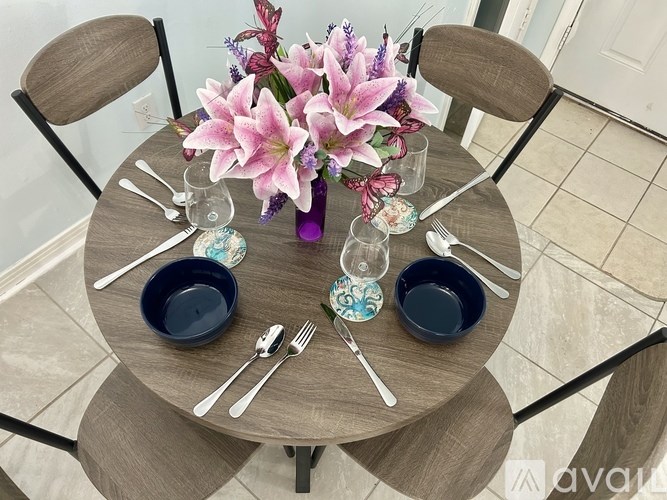 A table set with plates, cutlery and a vase of flowers.