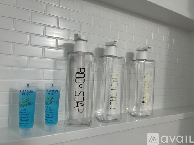 A bathroom shelf with body soap, body conditioner, and shampoo.