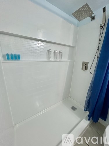 A white tiled bathroom with a blue shower curtain.