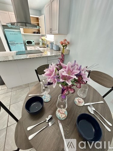 A dining table set with plates, cutlery and a vase of flowers.