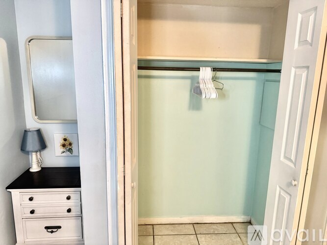 A bathroom with a white dresser and a blue shower.