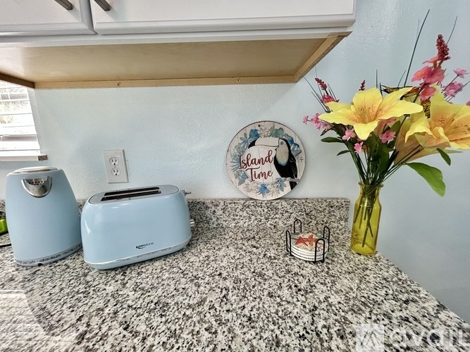 A kitchen counter with a toaster, a bread box, and a vase of flowers.
