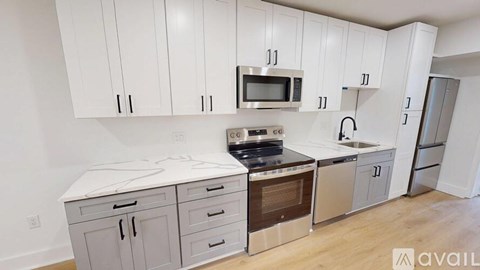 A kitchen with white cabinets and stainless steel appliances is available for rent.