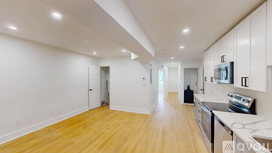 A spacious kitchen with wooden floors and white walls.