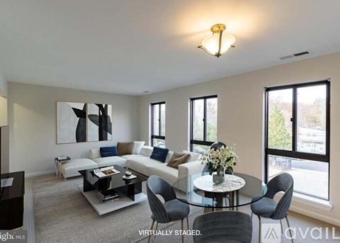 A living room with a glass table and chairs, a sofa, and a painting on the wall.