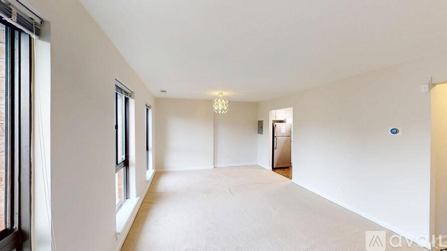 A spacious, empty room with a chandelier and a door at the end.