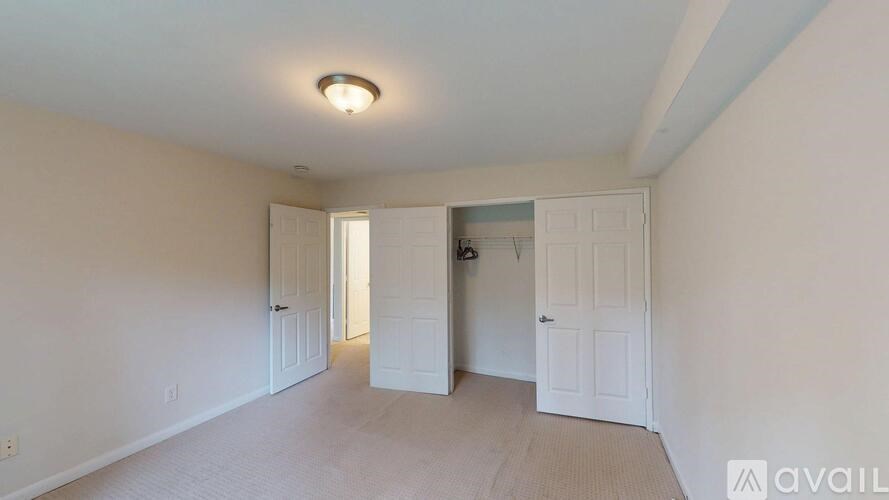 A room with white walls and a carpeted floor with a doorway leading to another room.