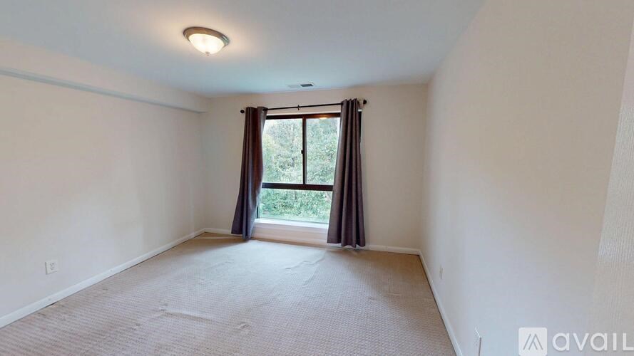 A room with a carpeted floor and a window with curtains.