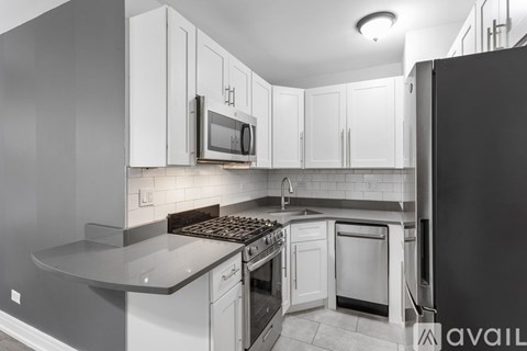 A kitchen with white cabinets and a black refrigerator.