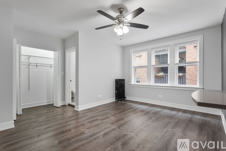 A spacious room with a ceiling fan and a window with a view of a brick building.