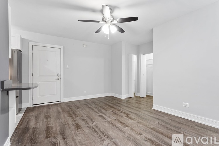 A room with a ceiling fan and wooden flooring.