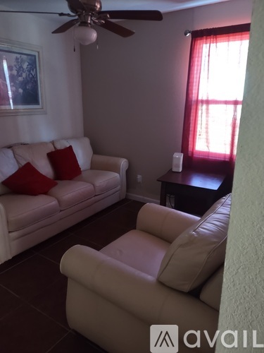 A living room with a white couch and a fan.