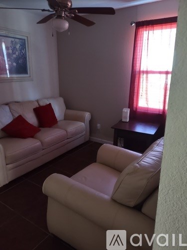 A living room with a white couch and a fan.