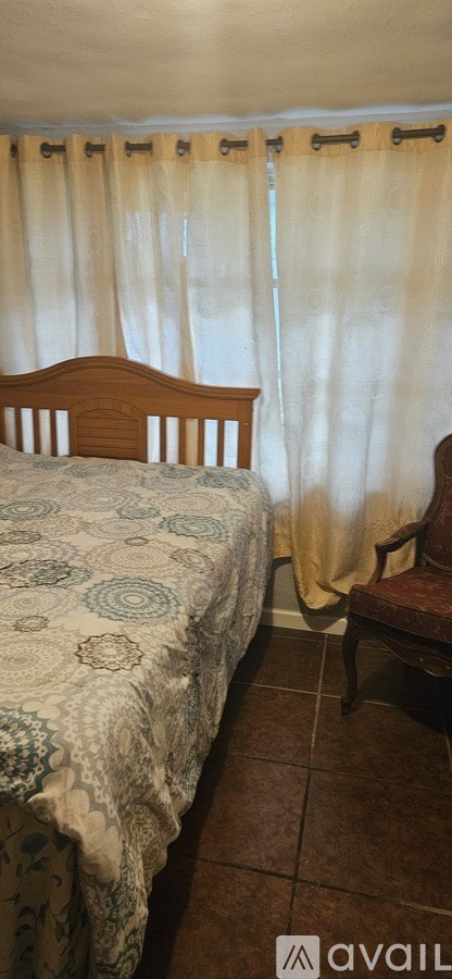 A bedroom with a bed and a chair.
