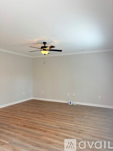 A room with a ceiling fan and wooden flooring.