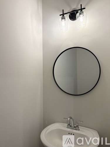A bathroom with a round mirror and a white sink.