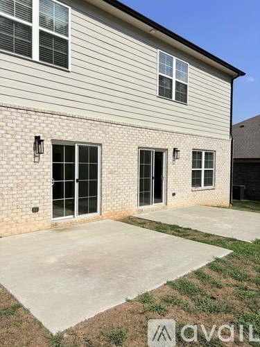 A house with a grey siding and a brown brick wall with a window and a door.