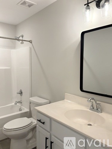 A white bathroom with a toilet, sink, and mirror.