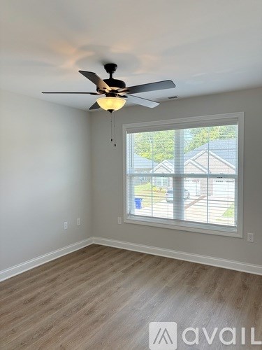 A room with a ceiling fan and a window overlooking a backyard.