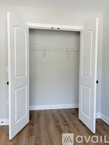 A white closet with a wooden floor and a white door.