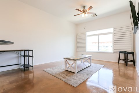 A living room with a white table and a rug in the center.