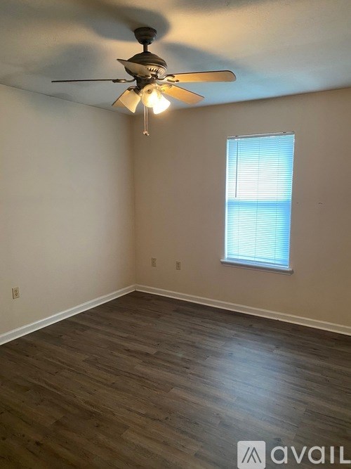 A room with a ceiling fan and a window with blinds.