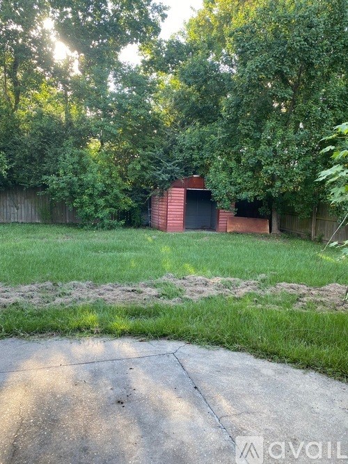 A backyard with a red building and a concrete path.