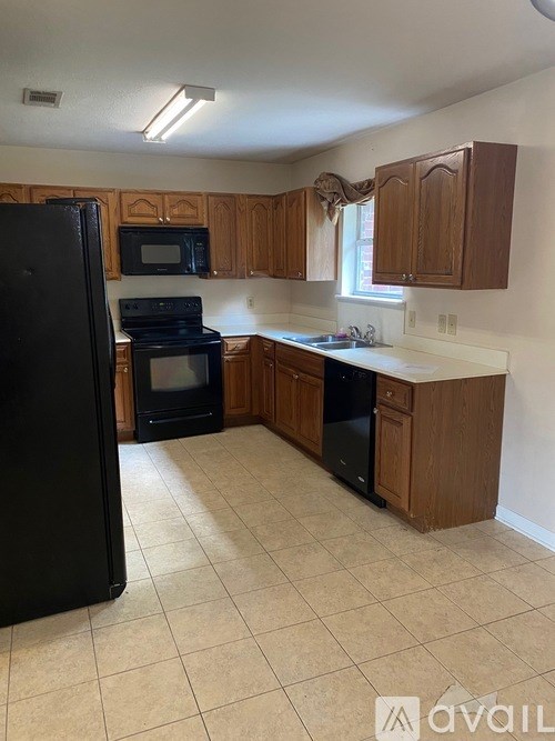 A kitchen with black appliances and wooden cabinets.