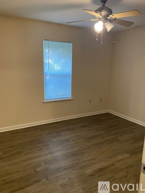 A room with wooden flooring and a ceiling fan with a light.