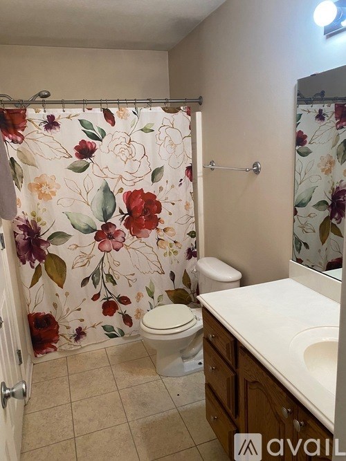 A bathroom with a floral shower curtain and a white toilet.