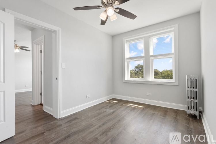 A room with a ceiling fan and a window with a view of trees outside.