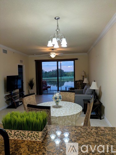 A living room with a television, chairs, and a table with a vase of flowers on it.