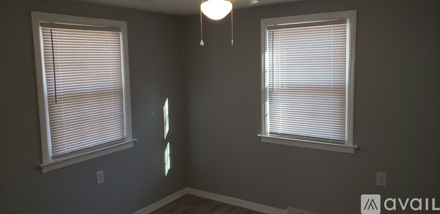 A room with two windows and a hanging light fixture.