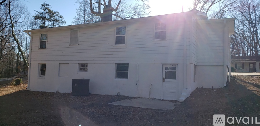 A white house with a black door and windows is available for purchase.