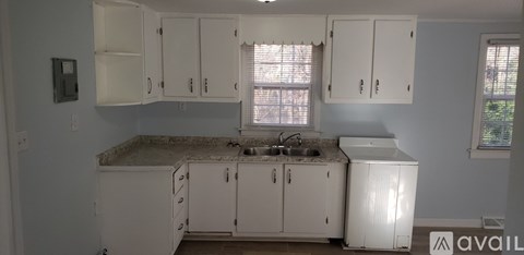 A kitchen with white cabinets and a granite countertop.