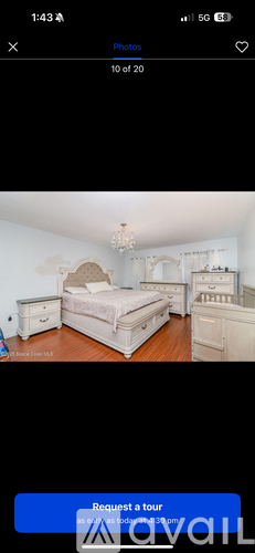 A bedroom with a large bed, dresser, and chandelier.