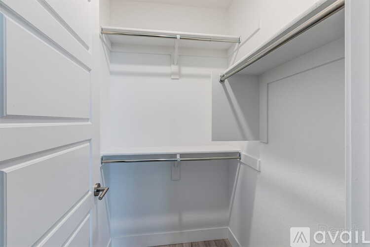 A white door is open to a small, empty room with a white ceiling and walls.